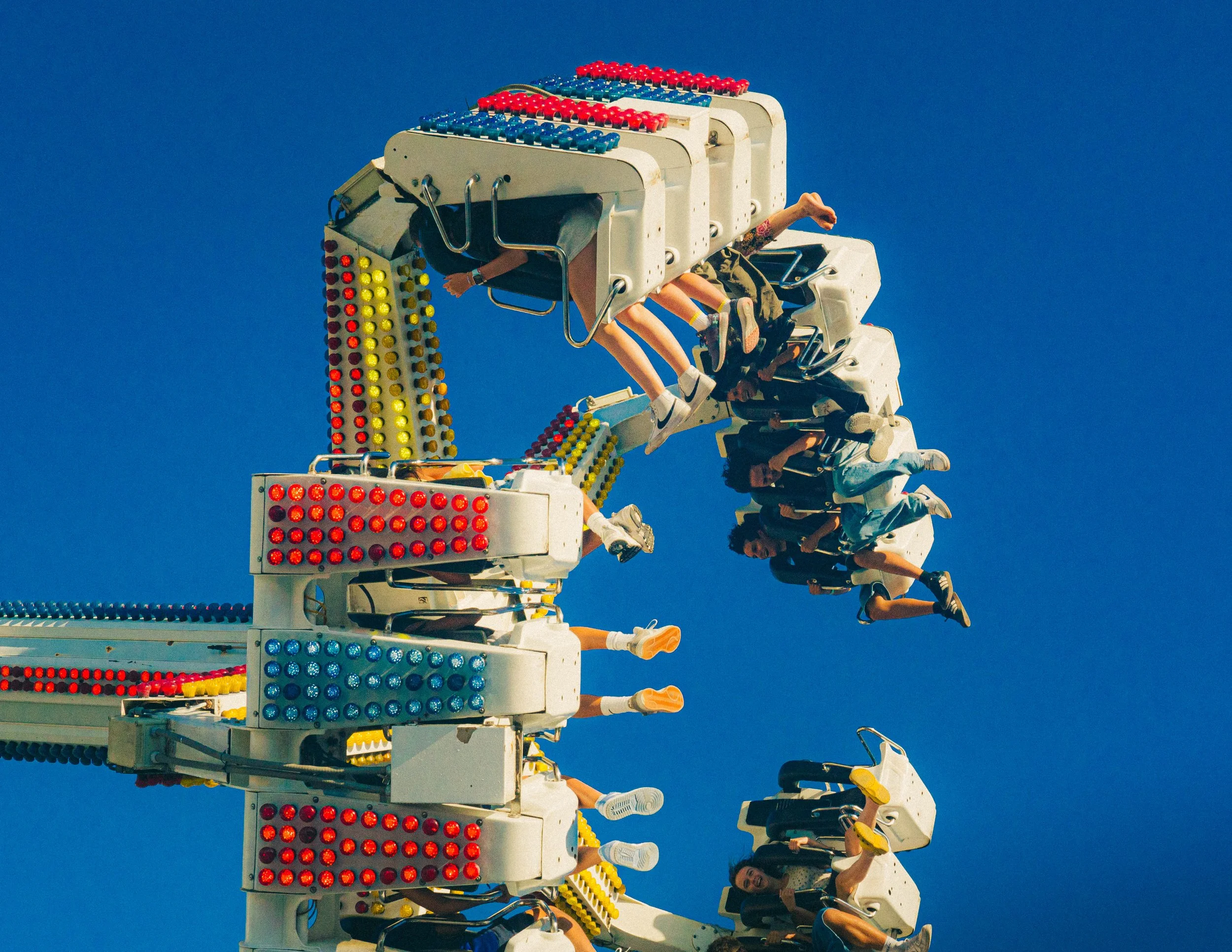 People riding a tall amusement park ride against a clear blue sky.