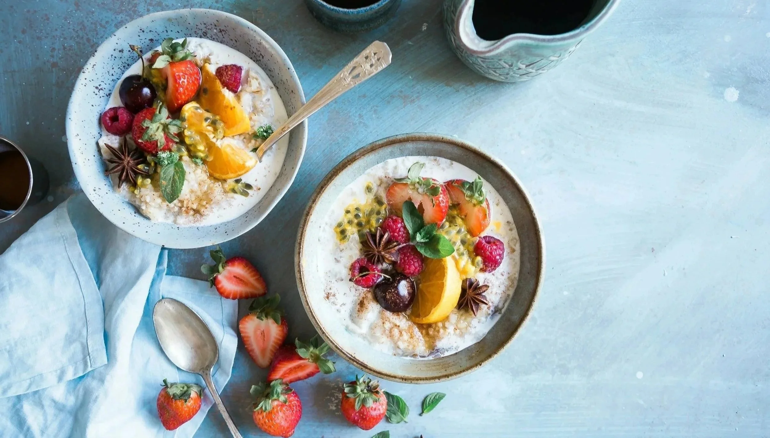 Two breakfast bowls of porridge topped with colourful fruit and seeds, depicting plant diversity in meals.
