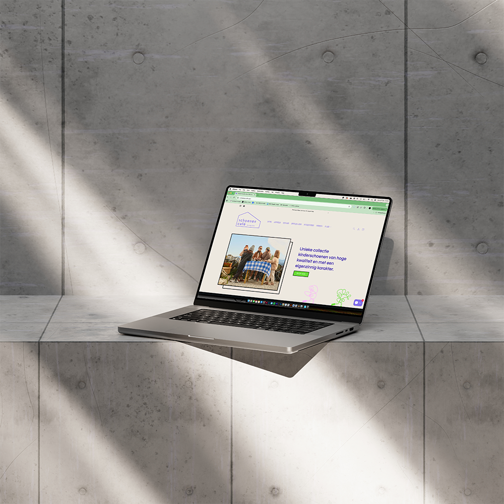 Opengeklapte laptop op een betonnen oppervlak met een website over kinderkleding op het scherm.