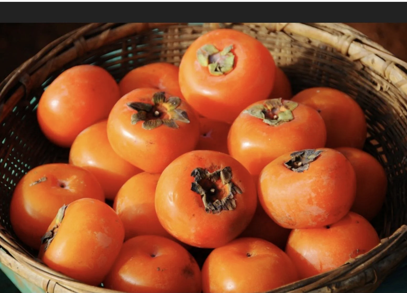 Basket of ripe Japanese persimmons with bright orange skin.