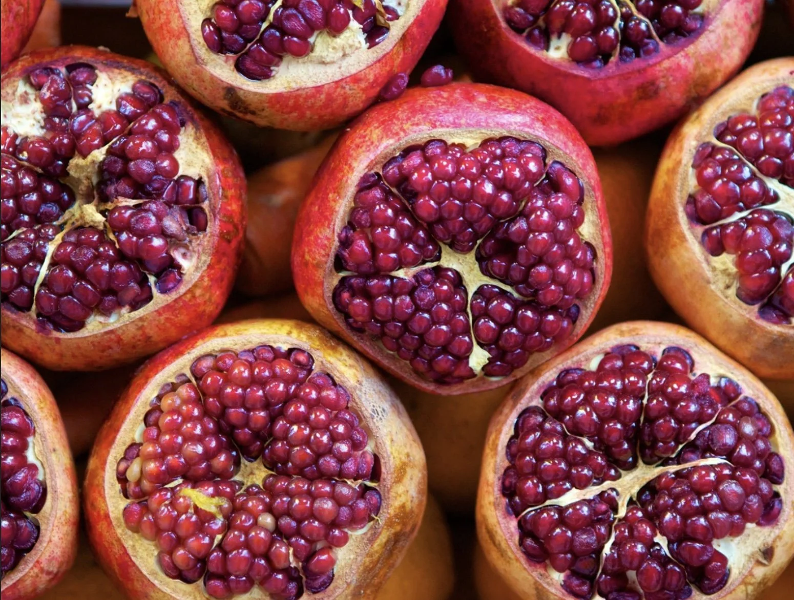 Close-up of halved pomegranates showing red seeds inside.
