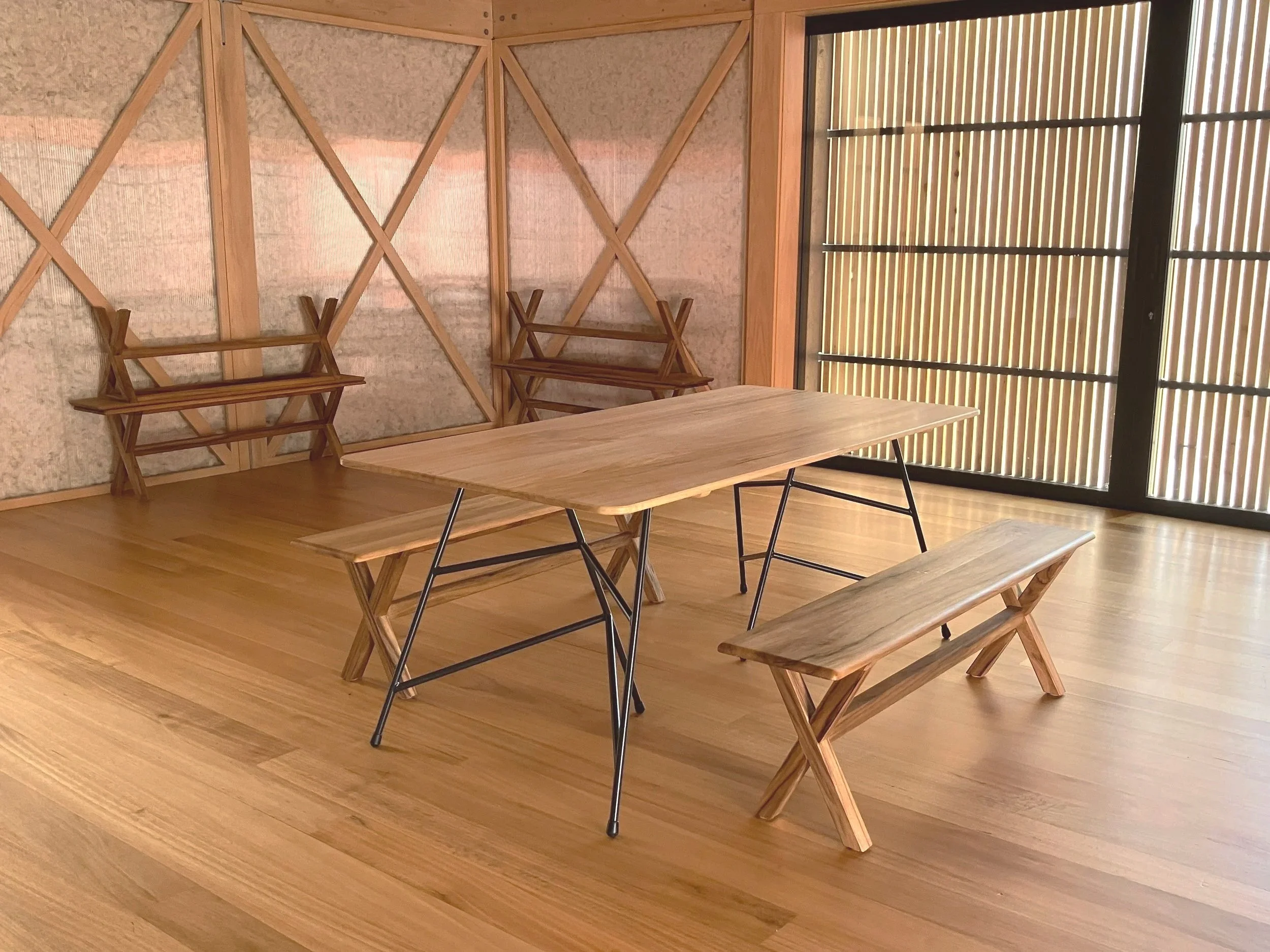 Timber interior room with Victorian Ash walls, Tasmanian Oak table, and black metal chairs. The room has vertical wooden slats on the right wall and exposed timber beams on the left wall.