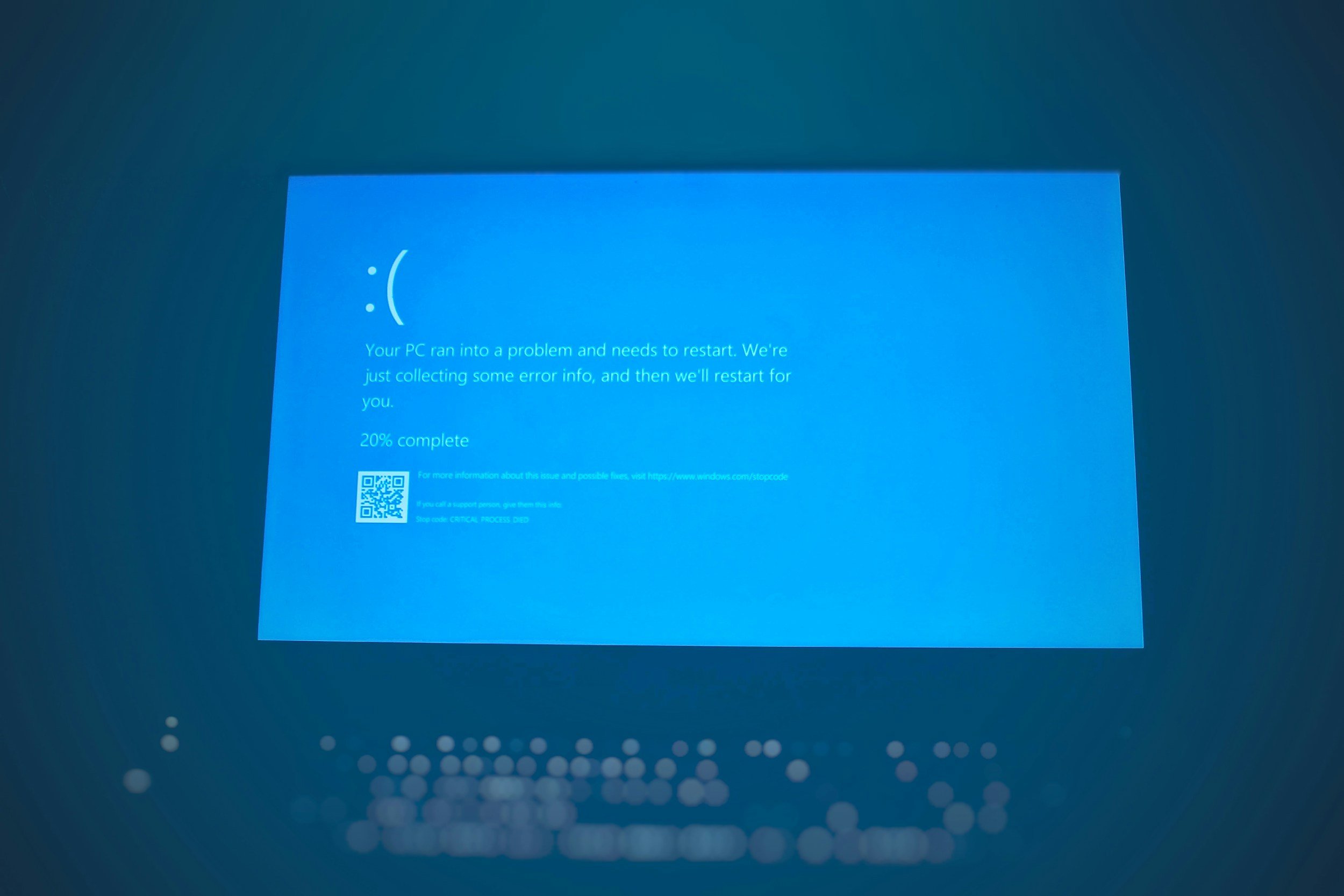 Blue screen of a Windows computer displaying a critical error message indicating a system crash, with a sad face, a QR code, and instructions for more information.