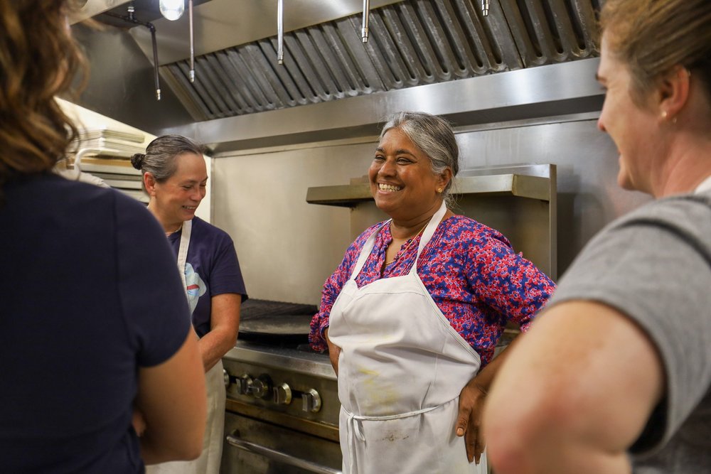 Chef Vimala laughing with friends in the kitchen