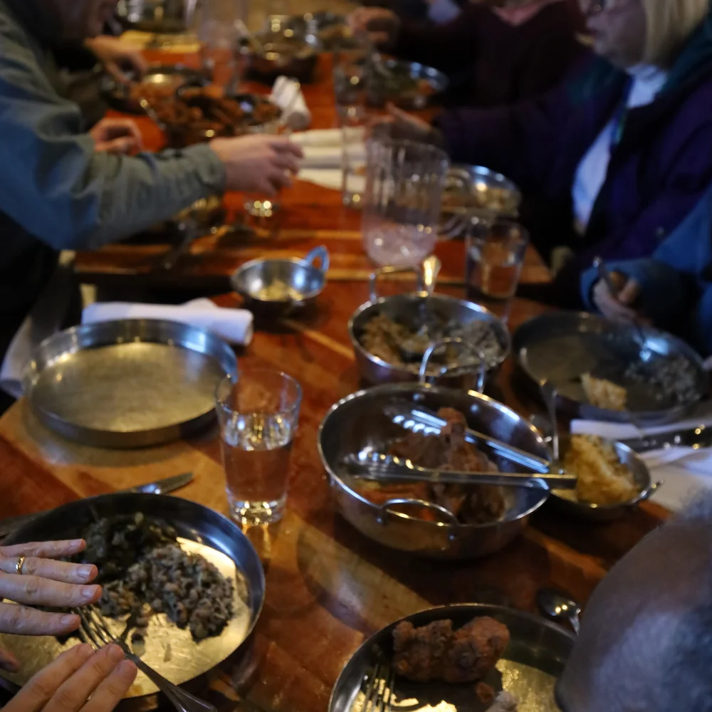 Guests sharing a family-style Curryblossom meal, kadhai bowls on the table