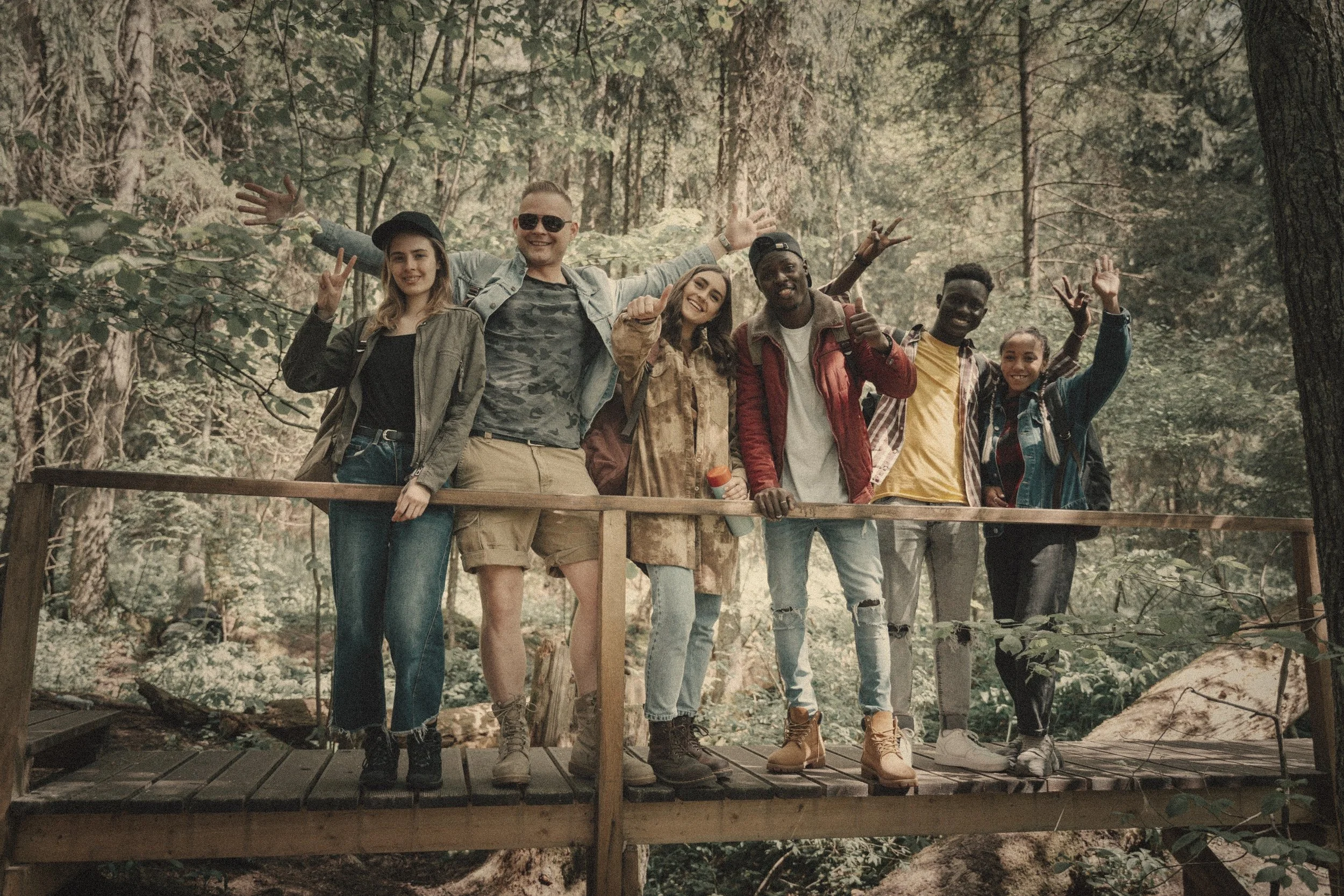 Diverse group of friends enjoying an outdoor adventure and nature hike on a wooden bridge