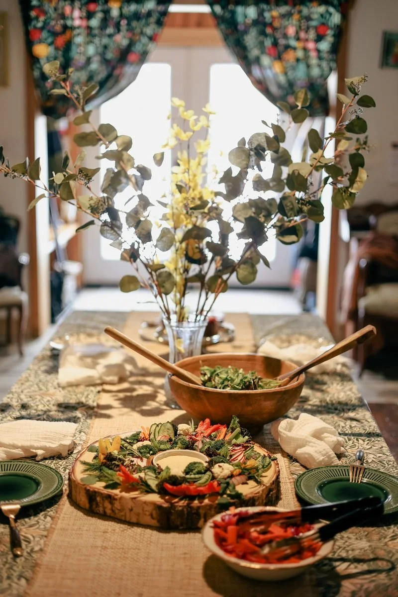 Beautifully decorated dining table with fresh salad, vegetable platter, and eucalyptus centerpieces