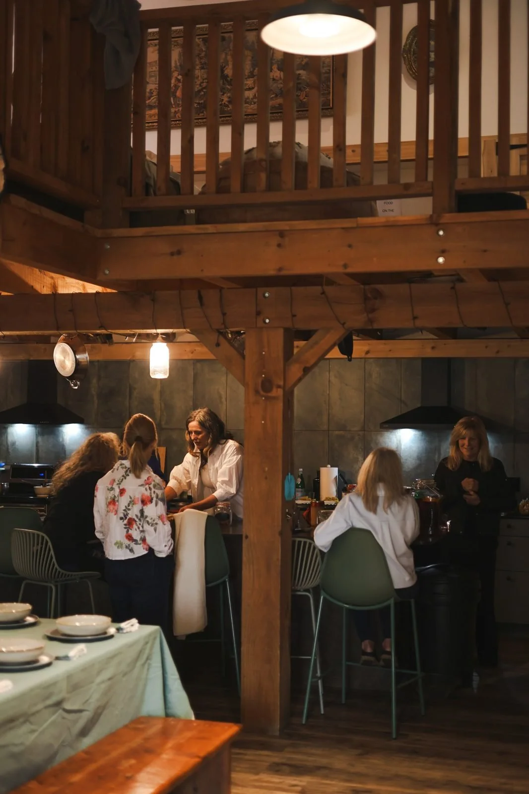 Guests gathering and chatting in a cozy, warm-lit lodge kitchen during an evening retreat event