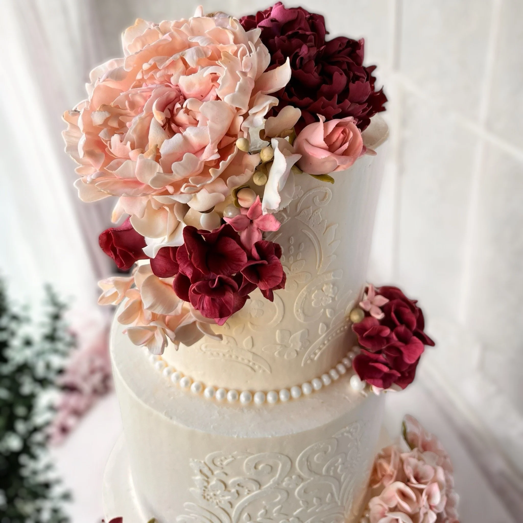 Top view of a 3 tier wedding cake with pearls and various shades of pink sugar flowers