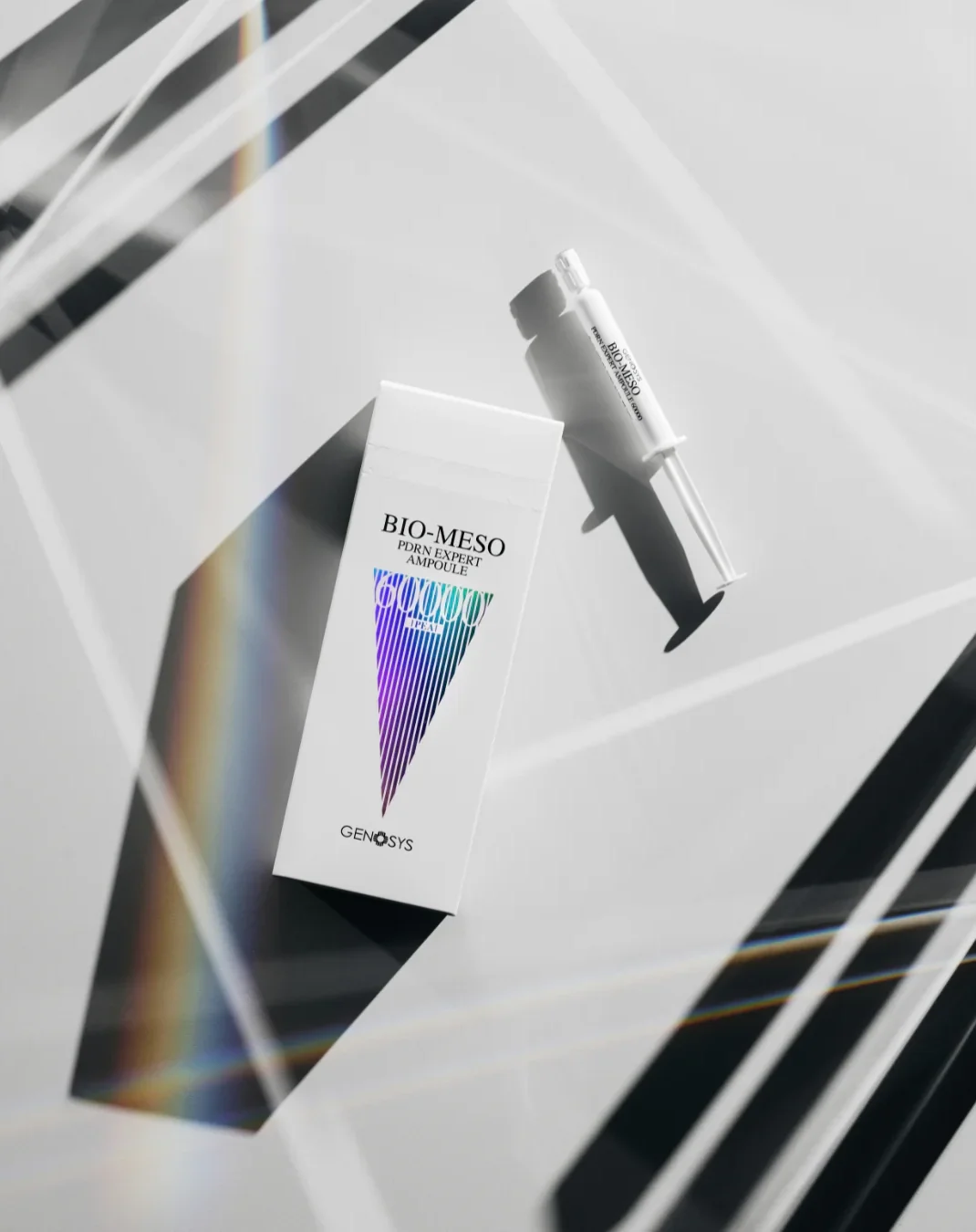 A box and syringe of BIO-MESO PDRN Expert Ampoule skincare product on a white surface with geometric shadows and rainbow light refraction.
