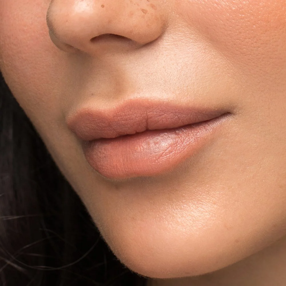 Close-up of a person's lips and part of their nose, showing smooth skin and natural lip color.