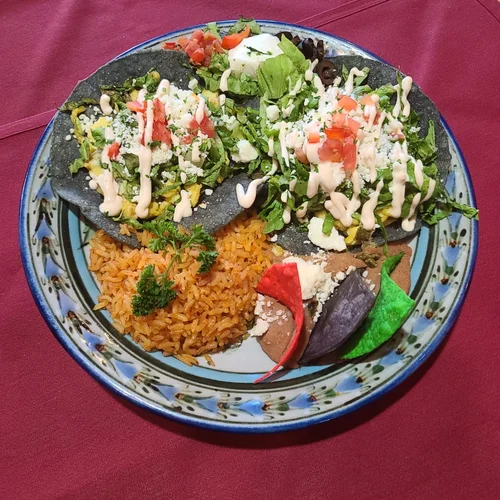 Blue corn tortillas topped with greens, crema and pico de gallo, with Spanish rice and refried beans