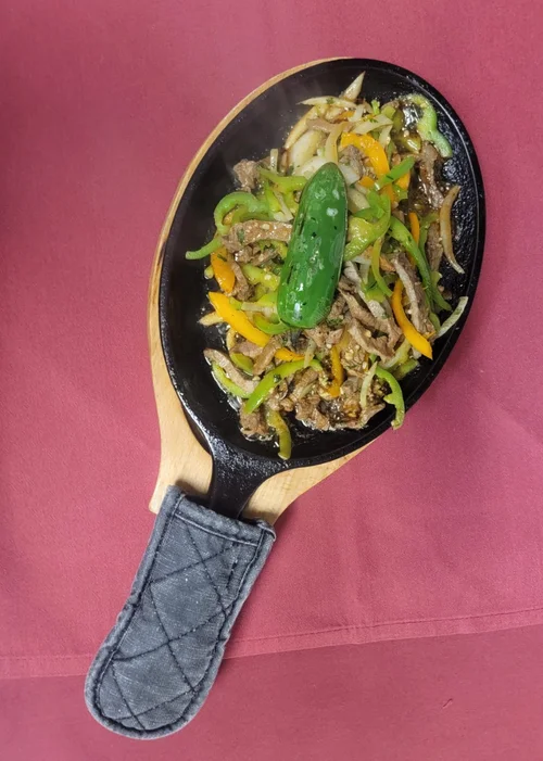 Fajitas with peppers and onions on a hot skillet