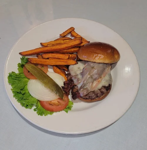 A burger with sweet potato fries, lettuce, tomato and pickle