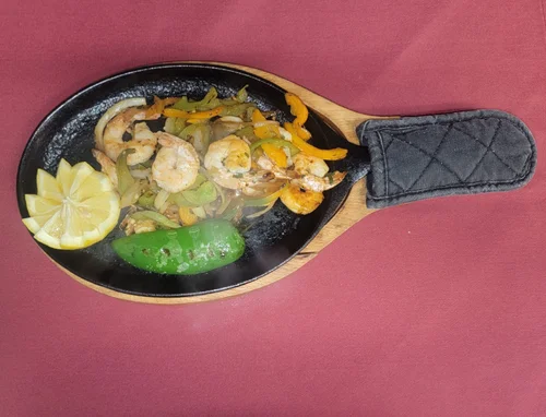 Shrimp fajitas with peppers and lemon on a cast-iron skillet