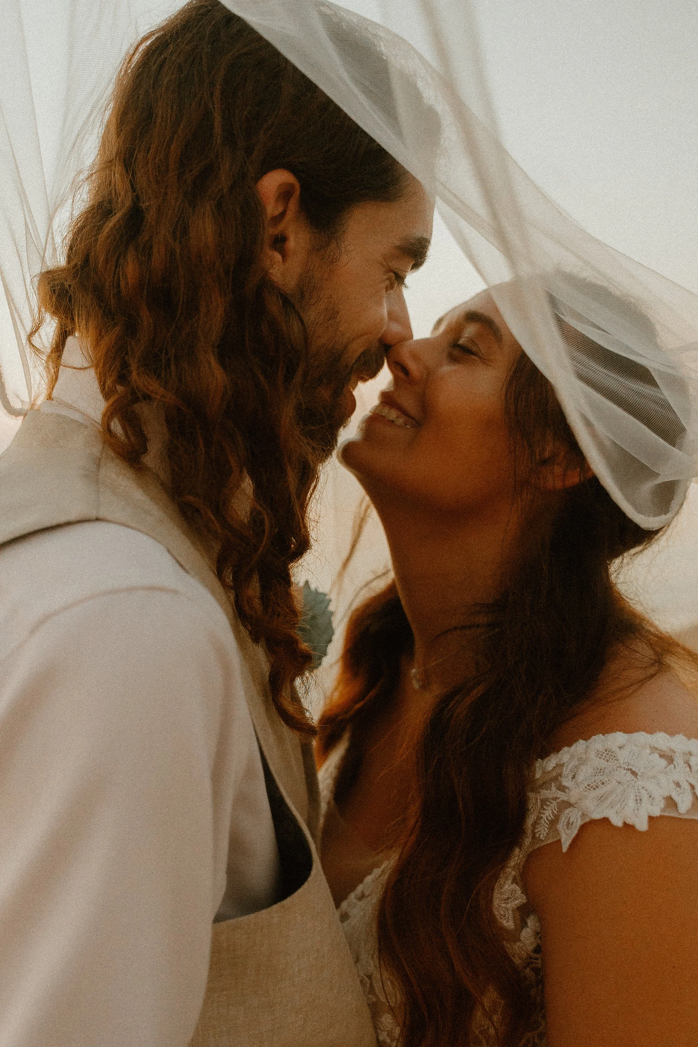 A couple sharing a close and intimate moment, with their foreheads touching and eyes closed.
