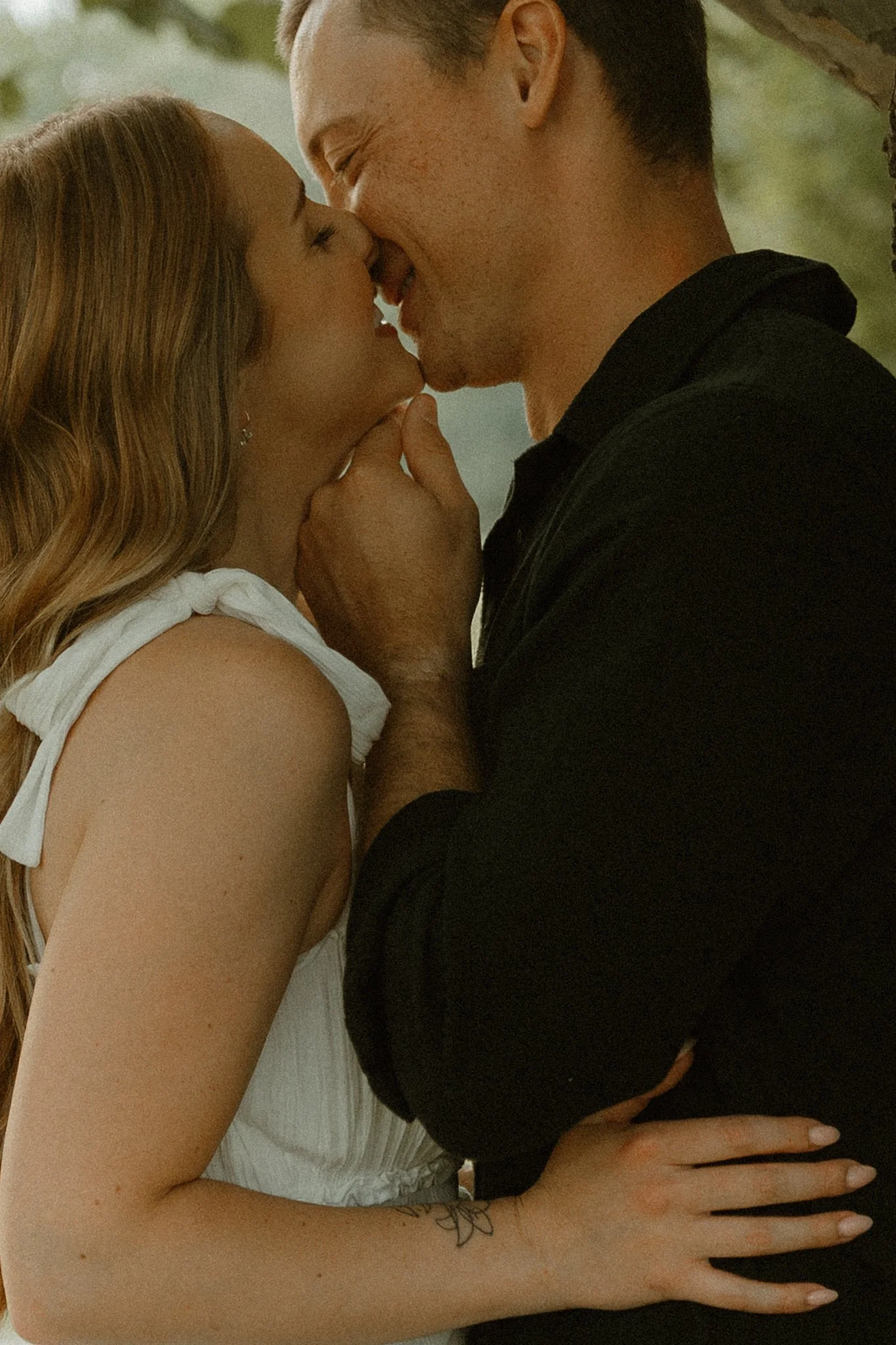 A couple close together, about to kiss, with the woman's hand on the man's chest and other on his shoulder.