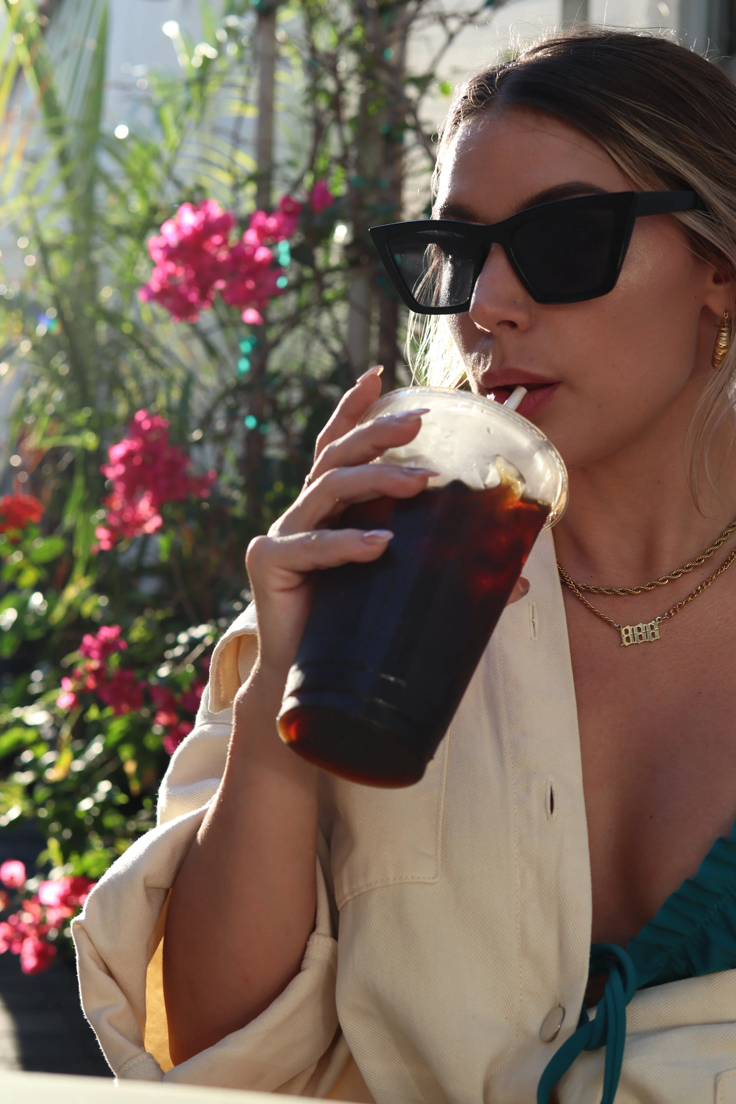 Woman in sunglasses among pink flowers, Selfcare Sundaze brand imagery