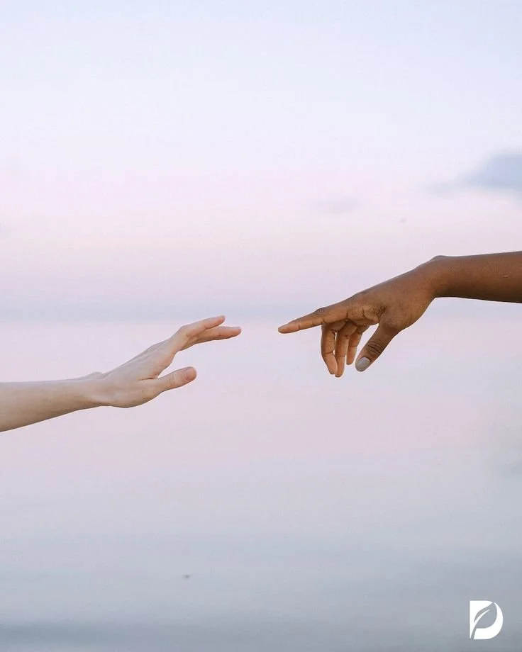 Two hands reaching towards each other with index fingers extended against a pastel sky background.