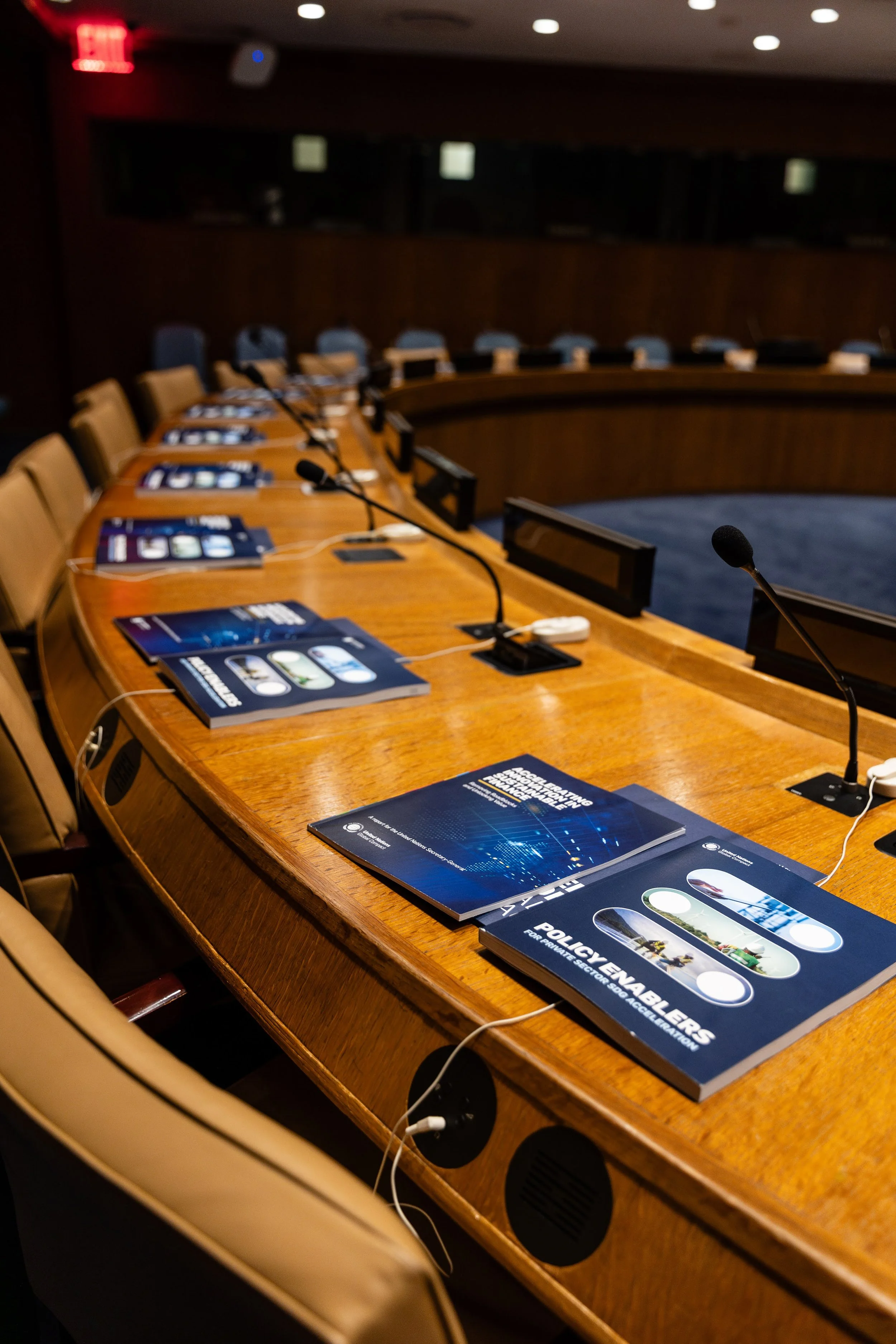 Copies of a UN Global Compact report set out at delegate seats in a conference chamber