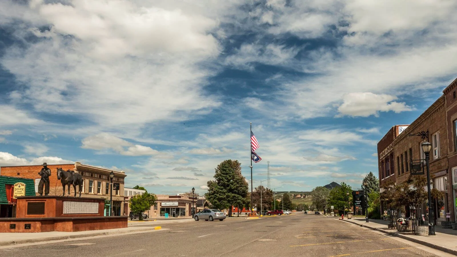 view from city street of cowboy and horse statue on one side and historic buildings on the other