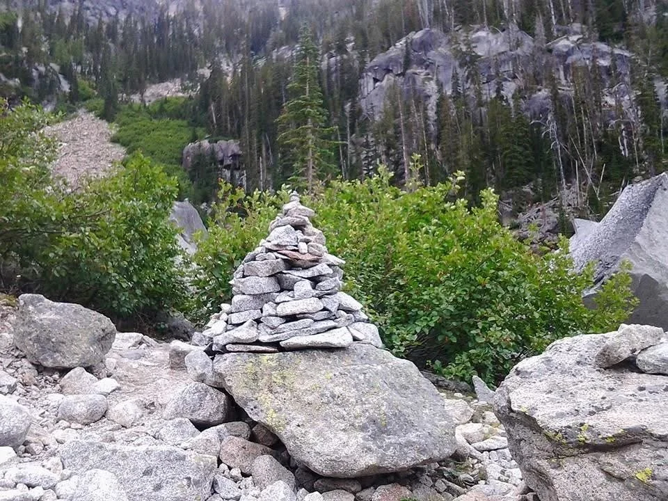 lots of little rocks formed into a cairn on top of one boulder