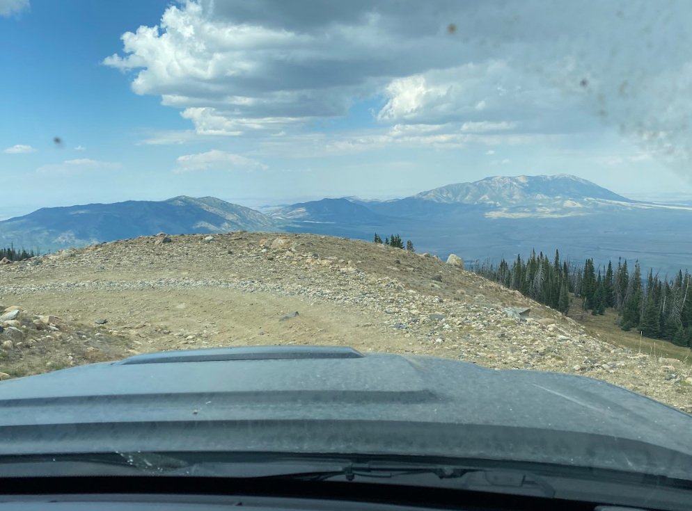 curve in gravel road with mountains in distant as seen through windshield
