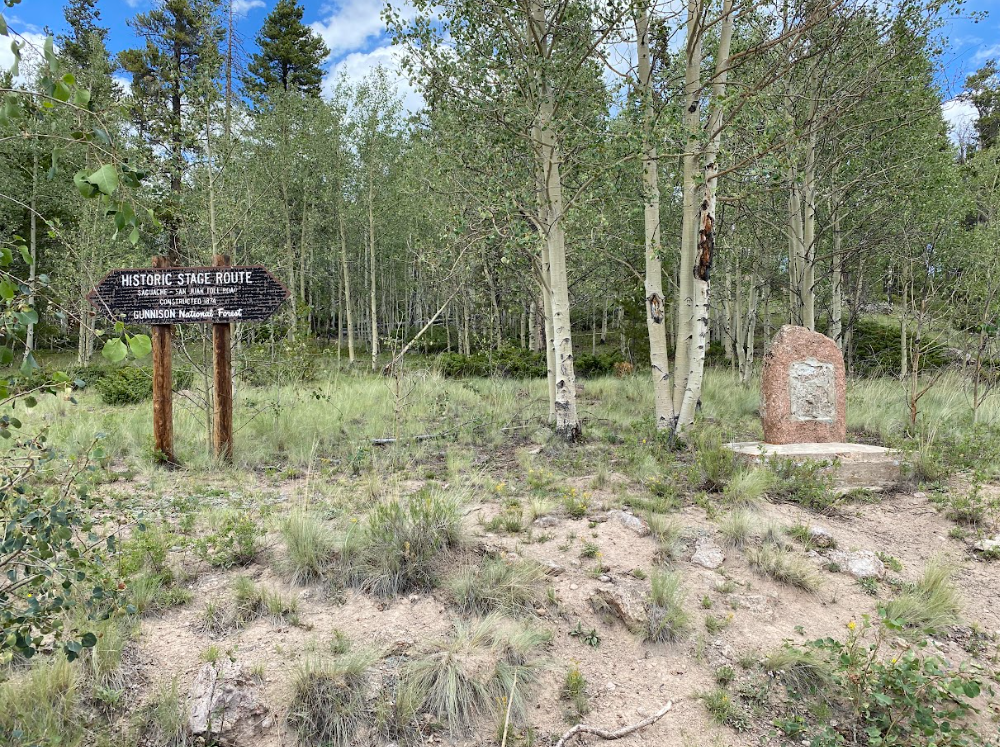forest of aspen trees with random concrete marker and wooden sign stating Historic Stage Roue Sagauche San Juan Toll Road Gunnison National Forest