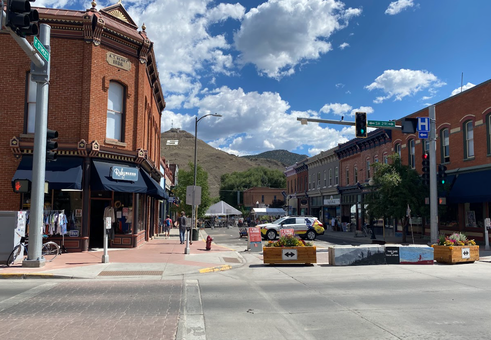 old west town of red brick buildings with a large white letter S on the hillside in the background