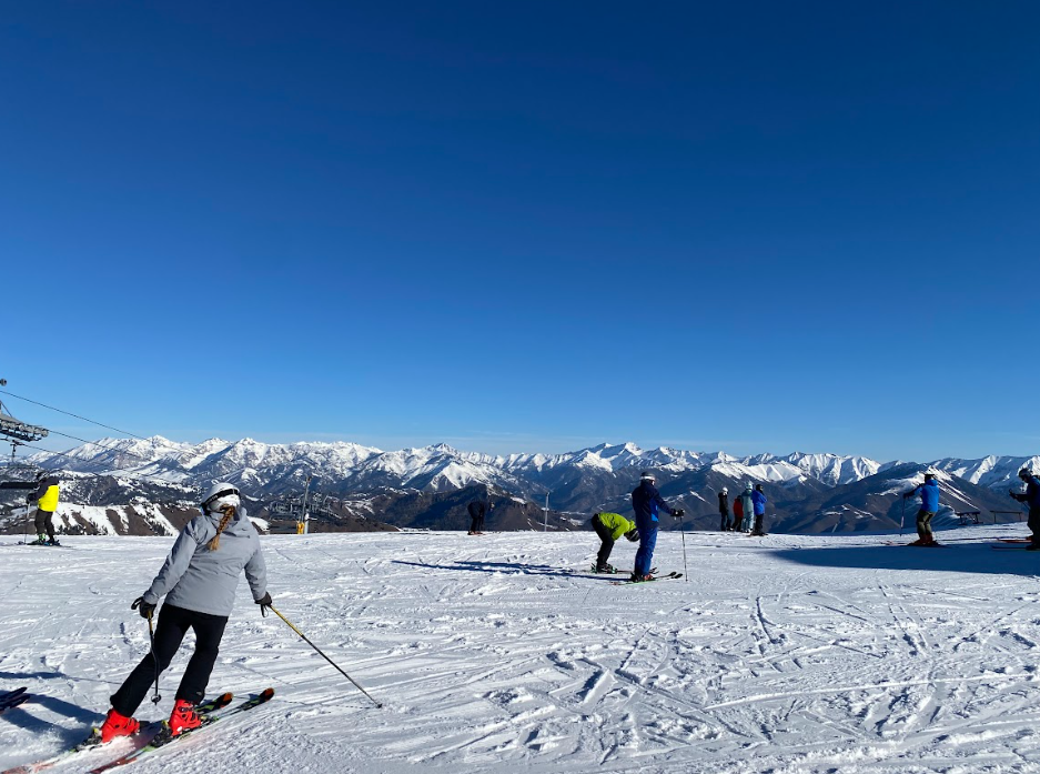 skiers on a flat ridge area looking out a the snowcapped Sawtooth mountain range