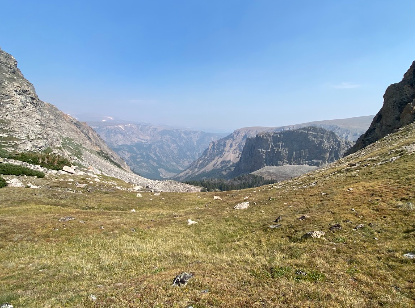 dry grass leads to a chasm with granite peaks on the opposite side