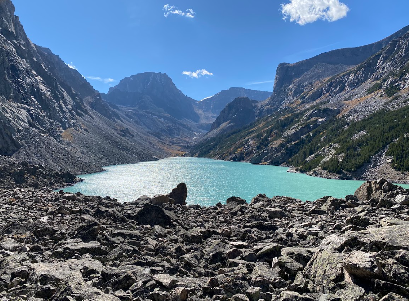 a turquoise colored lake sits between canyon walls glinting under a deep blue sky
