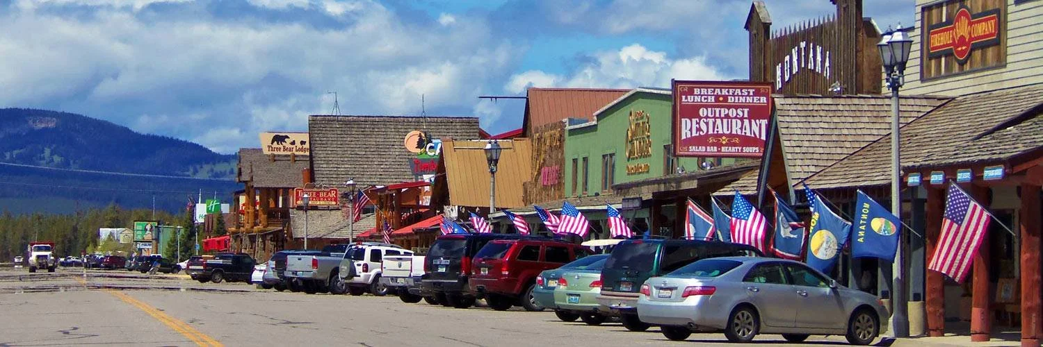 cars lined up in front of old west style buildings