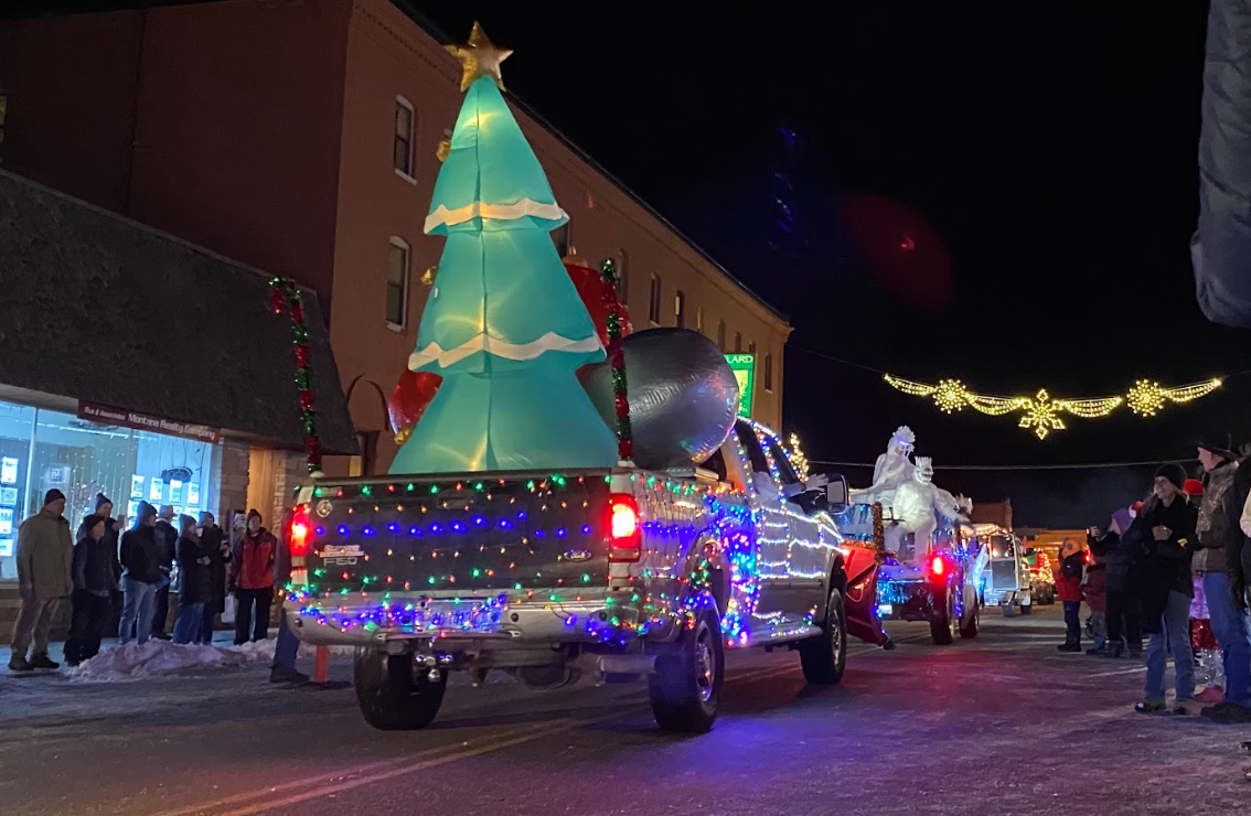 a parade of trucks decorated in Christmas lights and inflatables