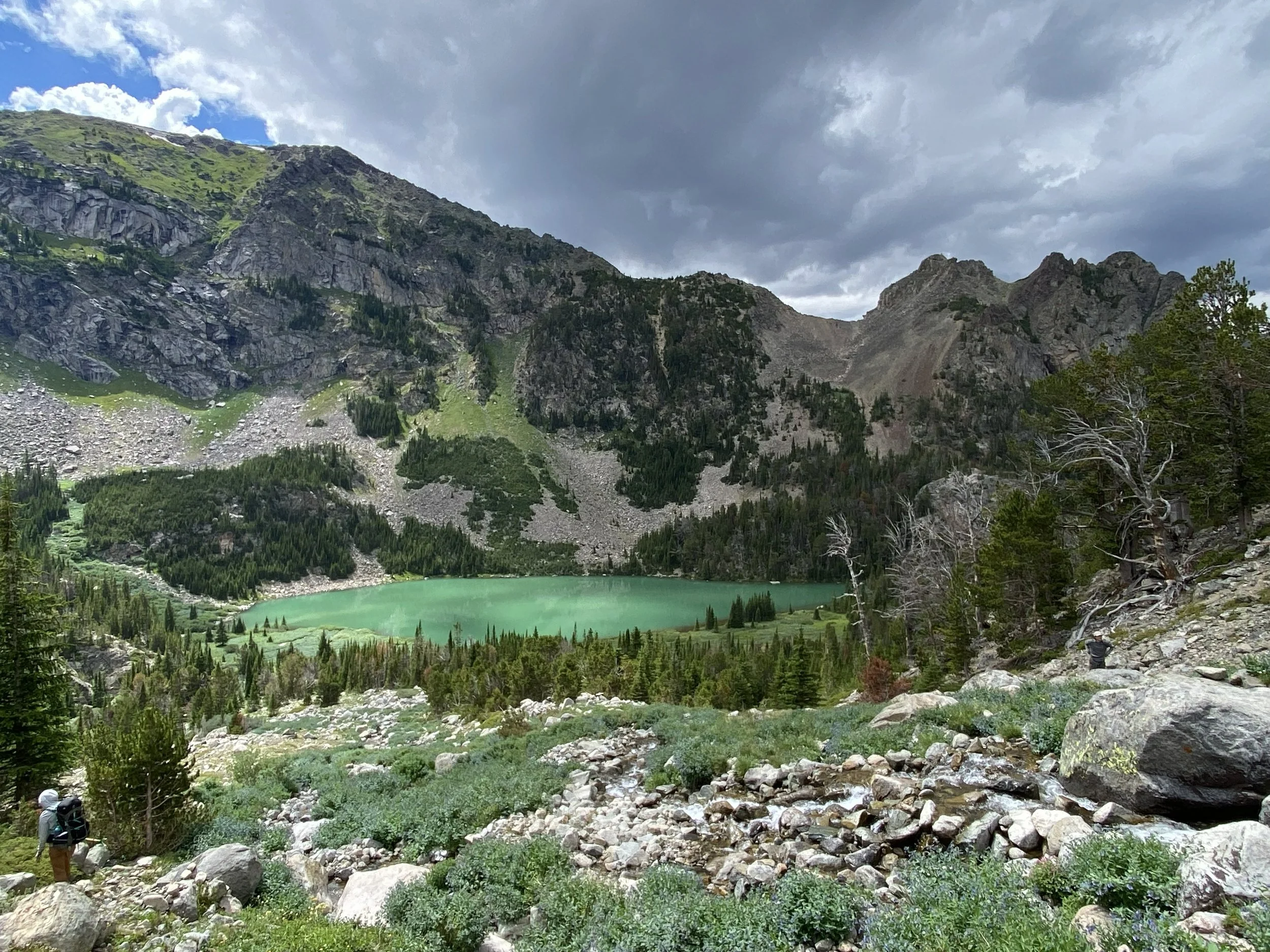 a jewel toned lake sits under a mountain ridgeline