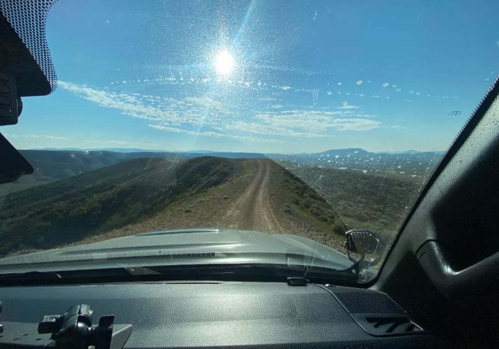 dirt road on a sunny day as seen through a dirty windshield