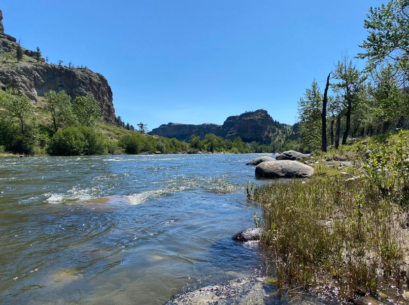 swirling water between a grassy bank and rock cliff walls