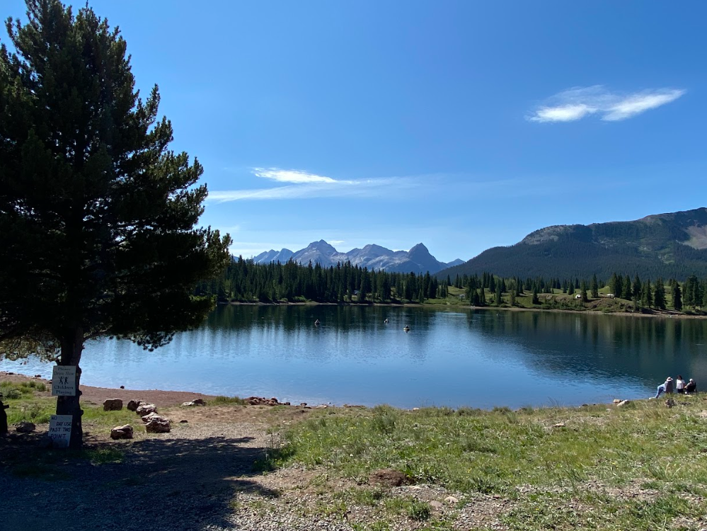 a lake scene with forests and mountains in background