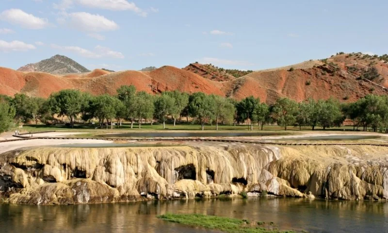 geothermal altered rocks beneath green trees and red hillsides