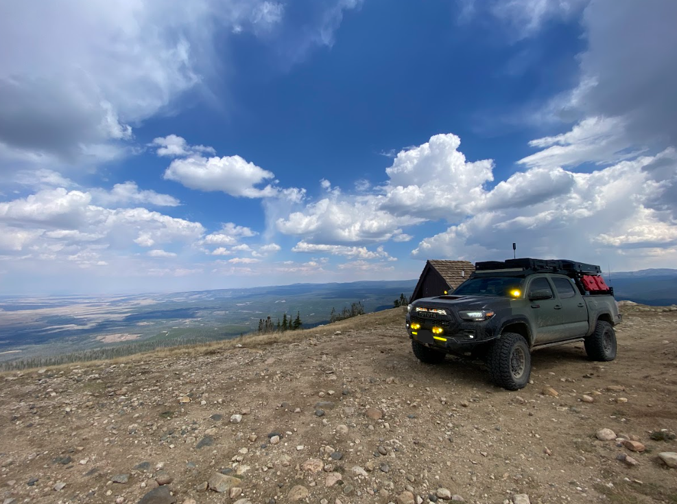 green truck on hillside overlooking large expanse of land