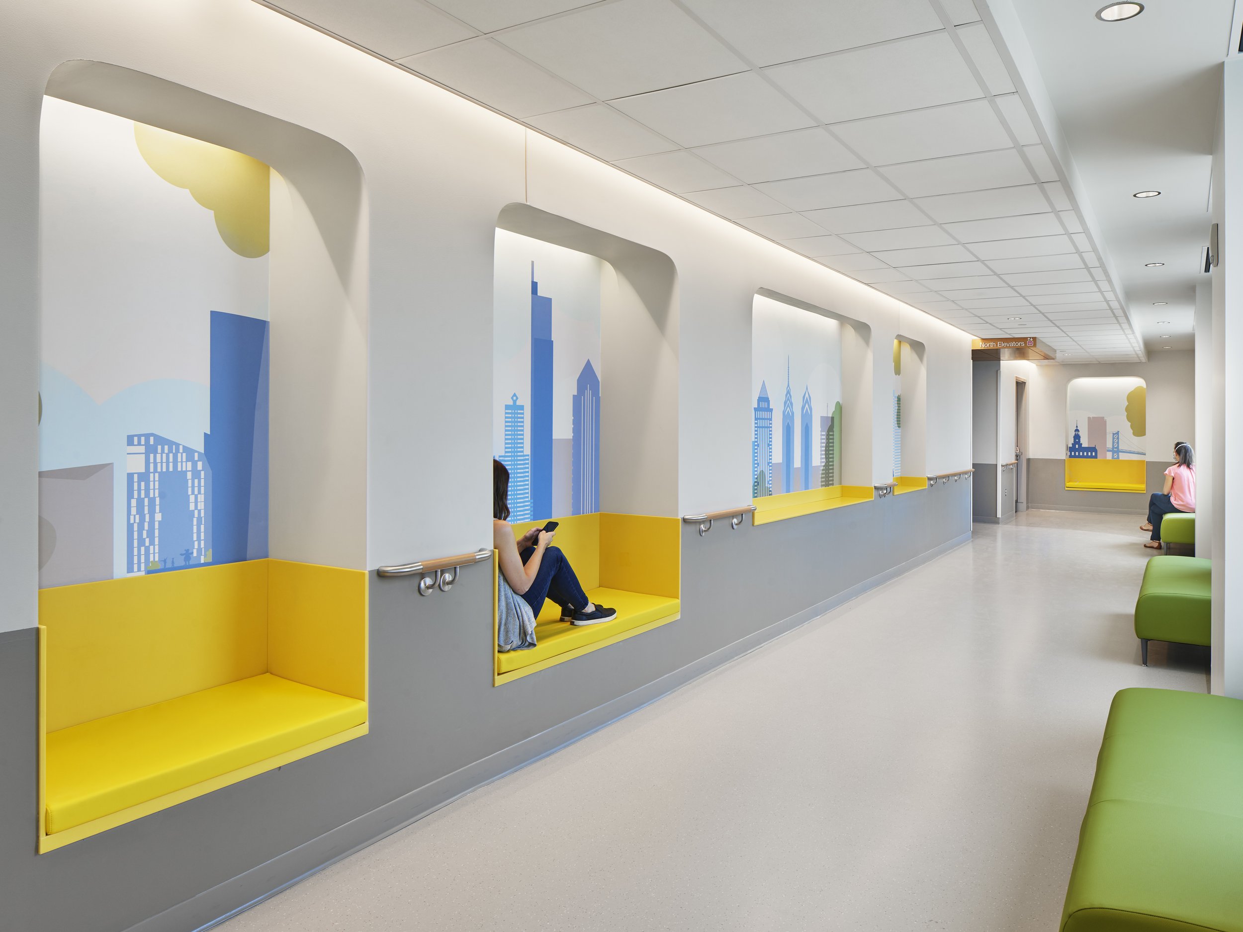 Healthcare corridor lighting design with linear cove lighting and illuminated seating niches.