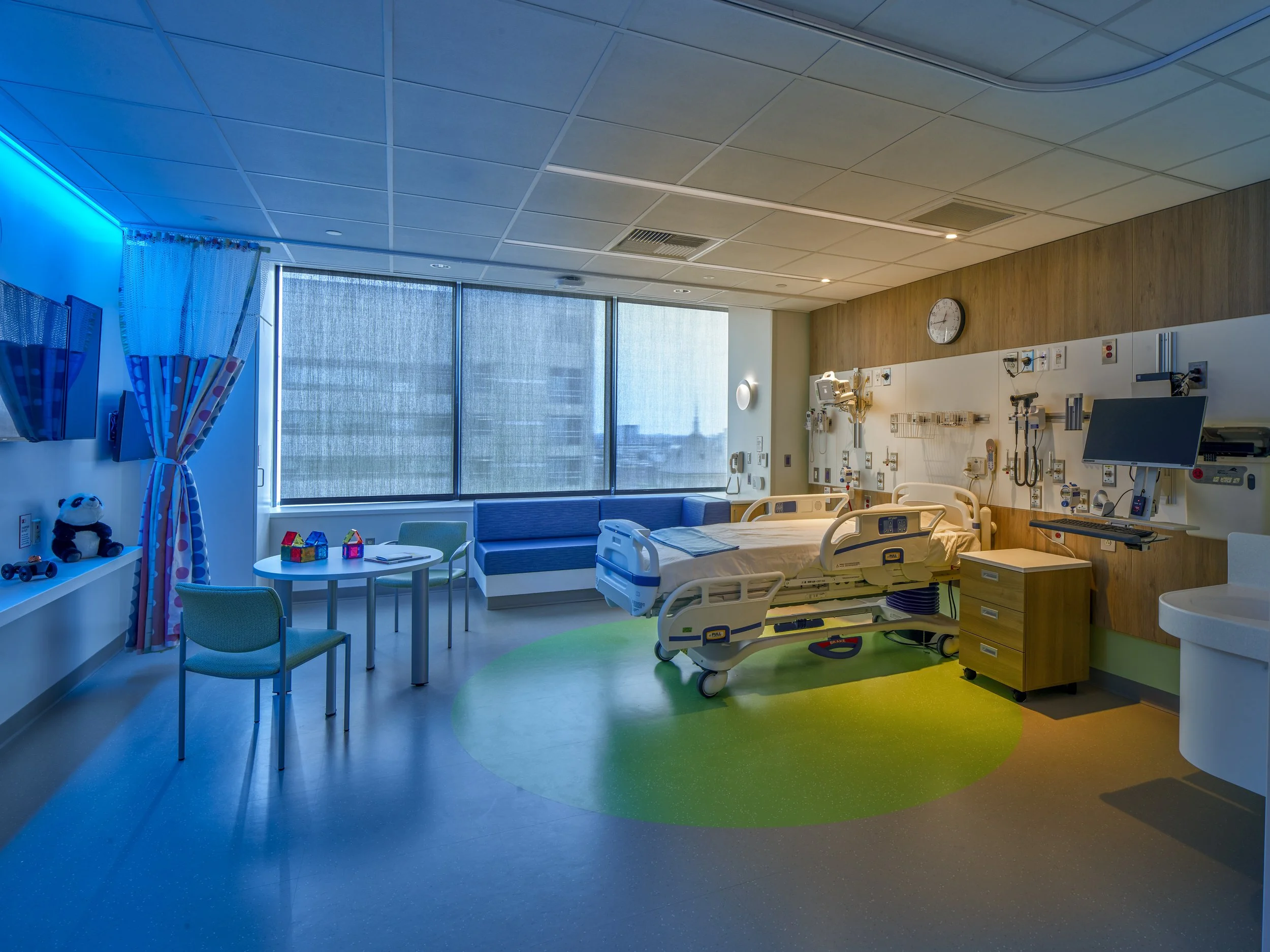 Healthcare patient room lighting design with color-changing cove lighting, tunable white circadian lighting, and a dimmed reading light.