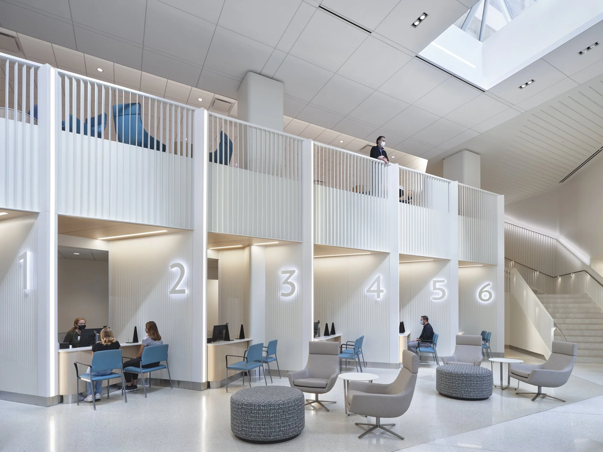 Modern healthcare lobby lighting design with linear lighting at check-in desks, creating a welcoming atmosphere.