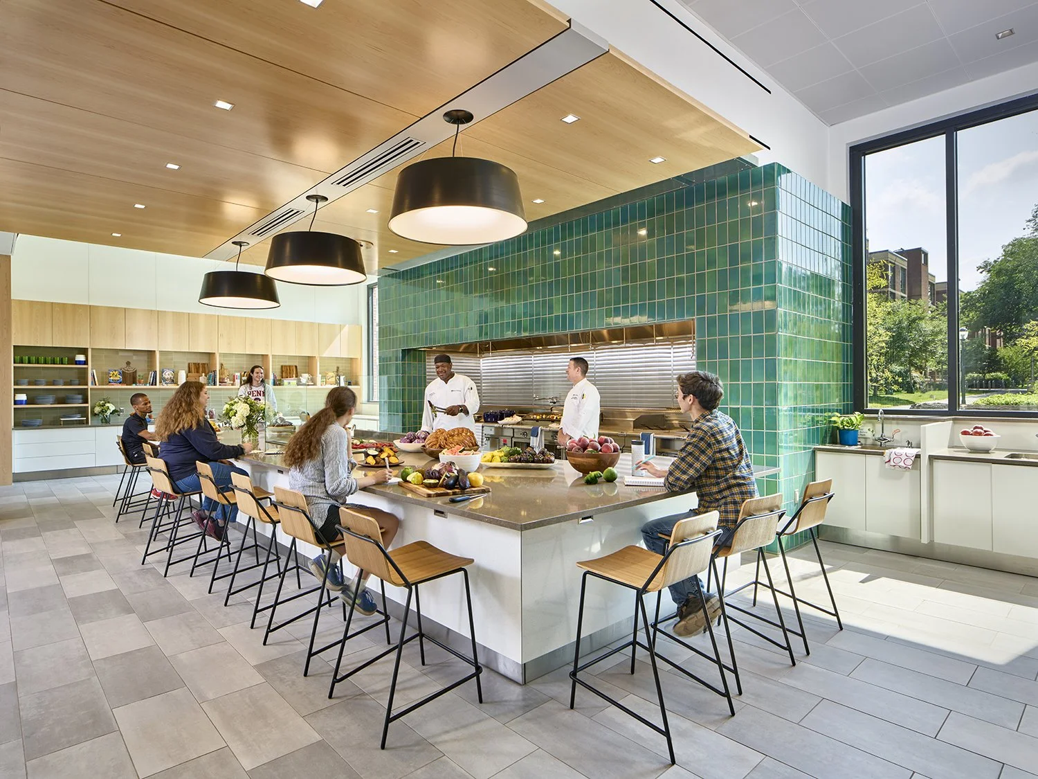 College dormitory teaching kitchen lighting design with decorative pendants over the island for community gatherings.