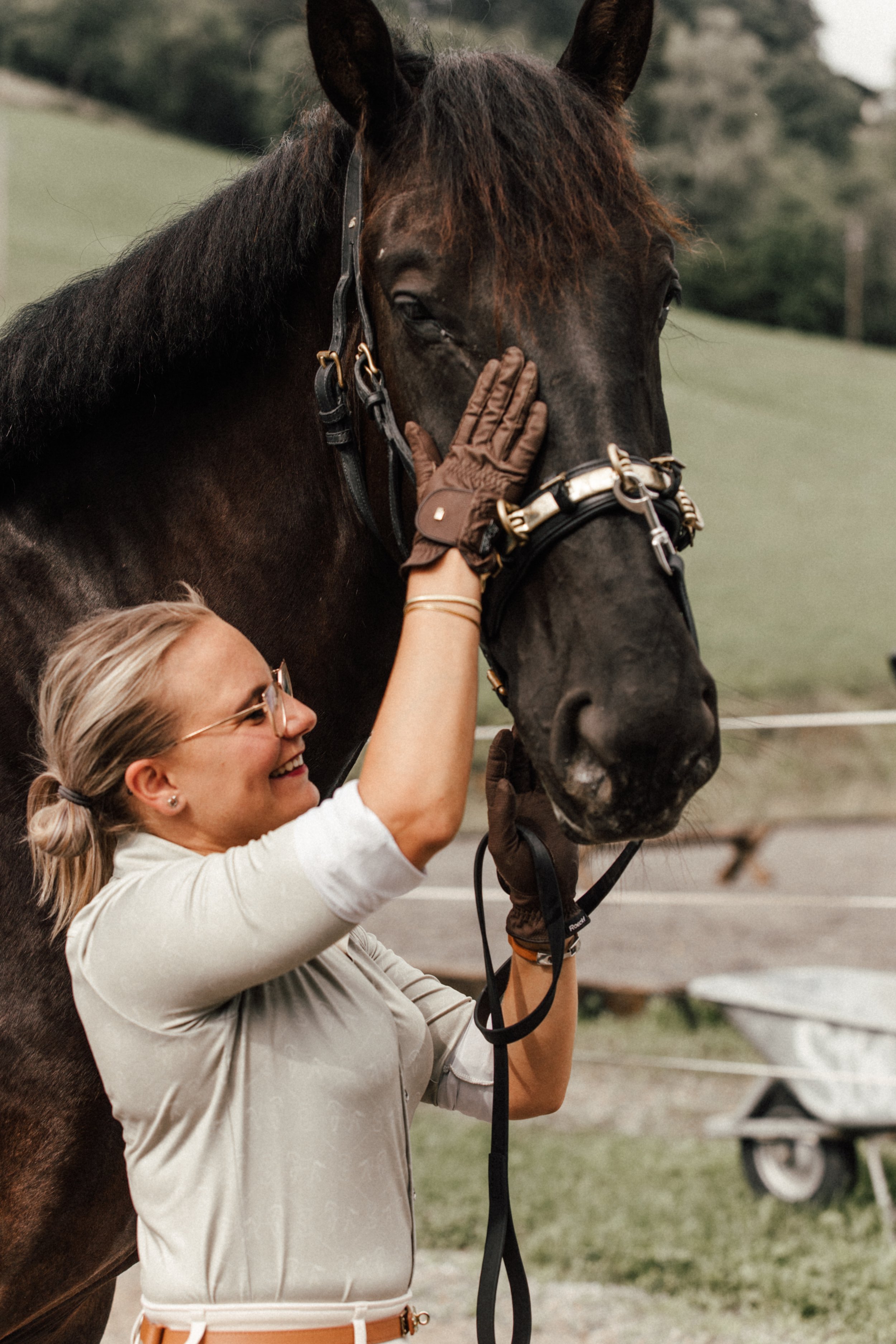 Frau pflegt ein schwarzes Pferd im Freien.