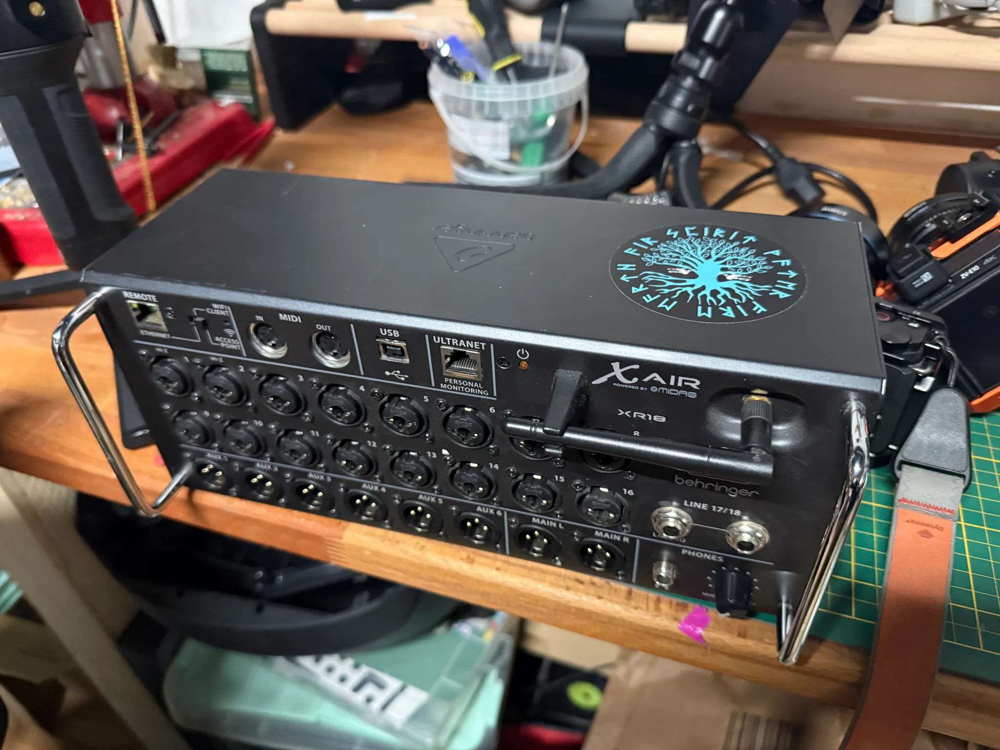 Ein elektronisches Audio- und Kommunikationsgerät auf einem Werkstatttisch, umgeben von Werkzeugen und Elektronikzubehör.