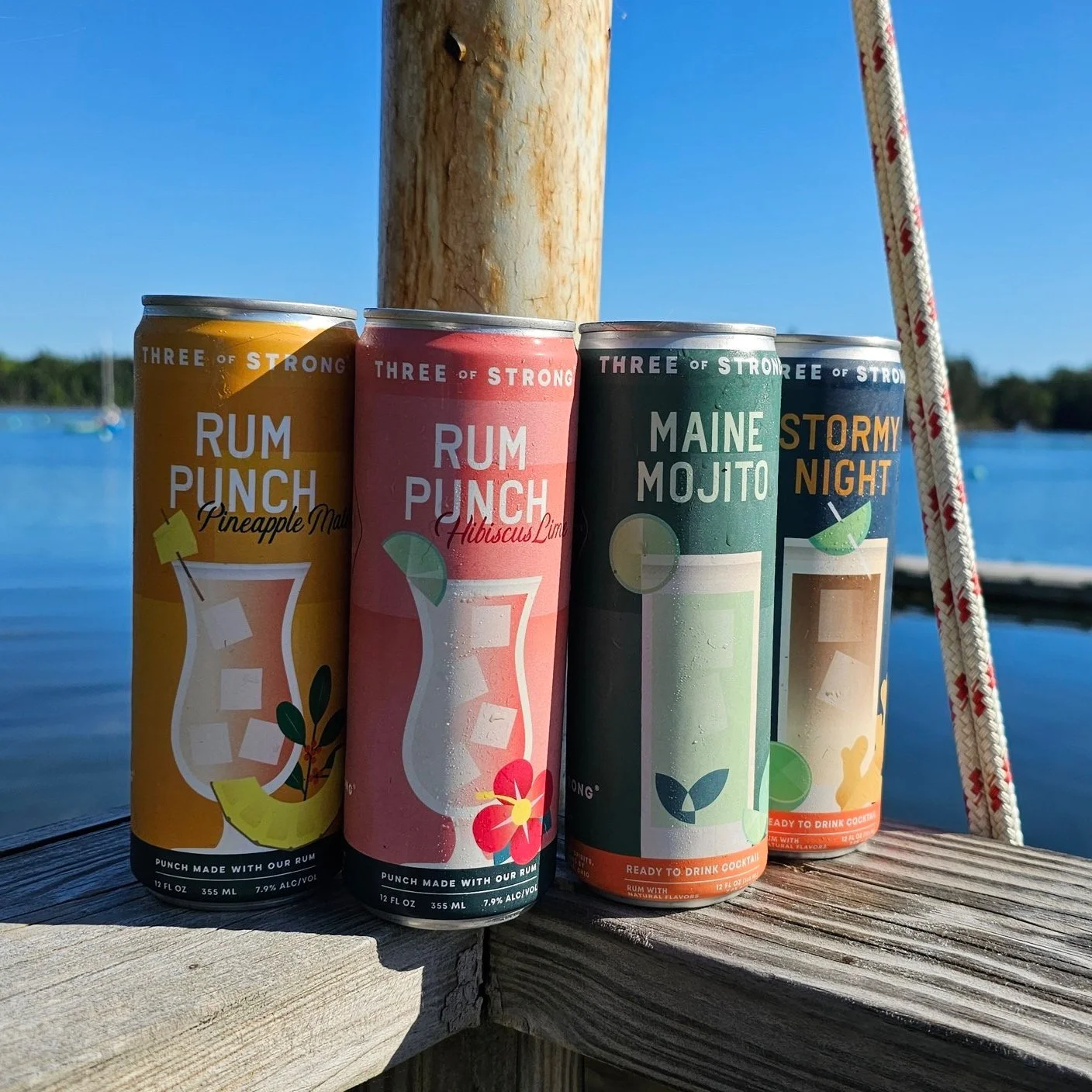 Two cans of Three of Strong's Ready to Drink Cocktails in front of a scenic landscape