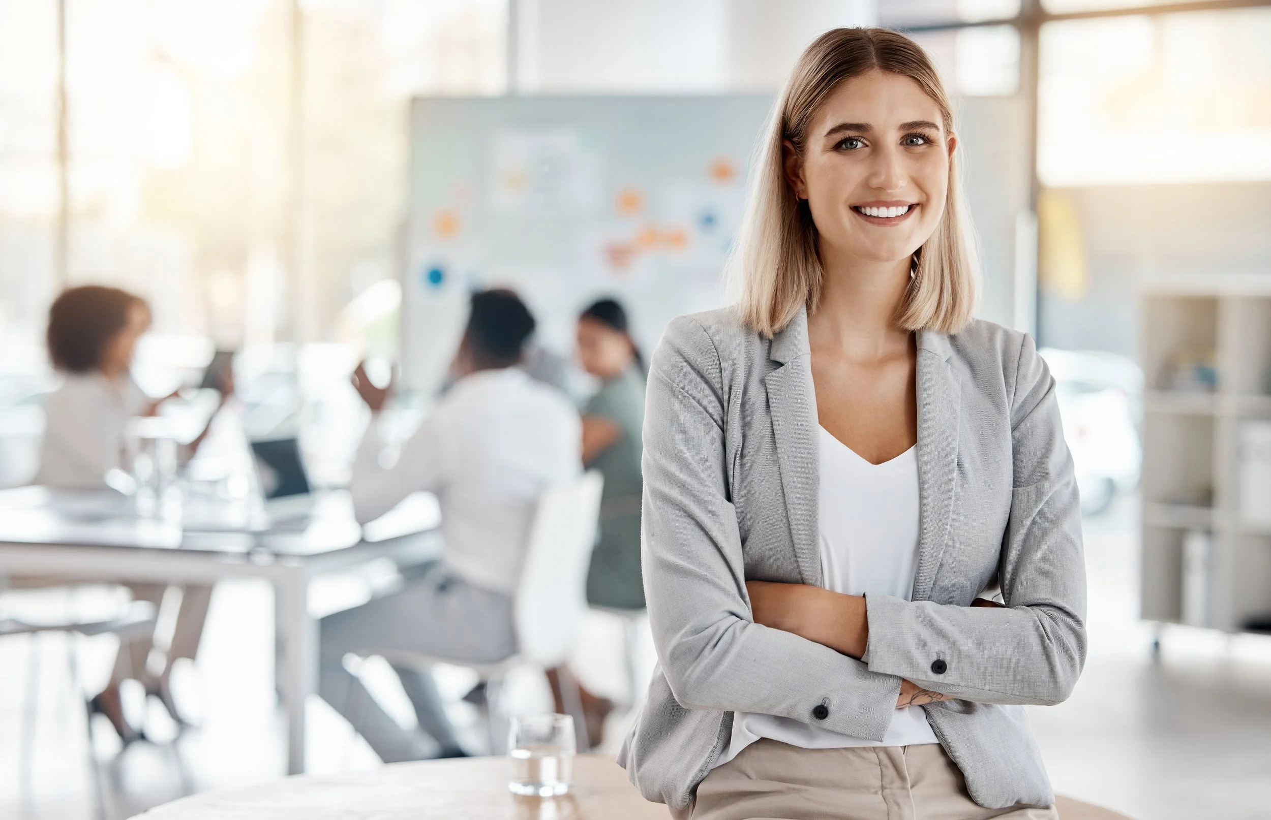 woman-employee-smiling-with-arms-crossed-gray-blazer-in-conference-room