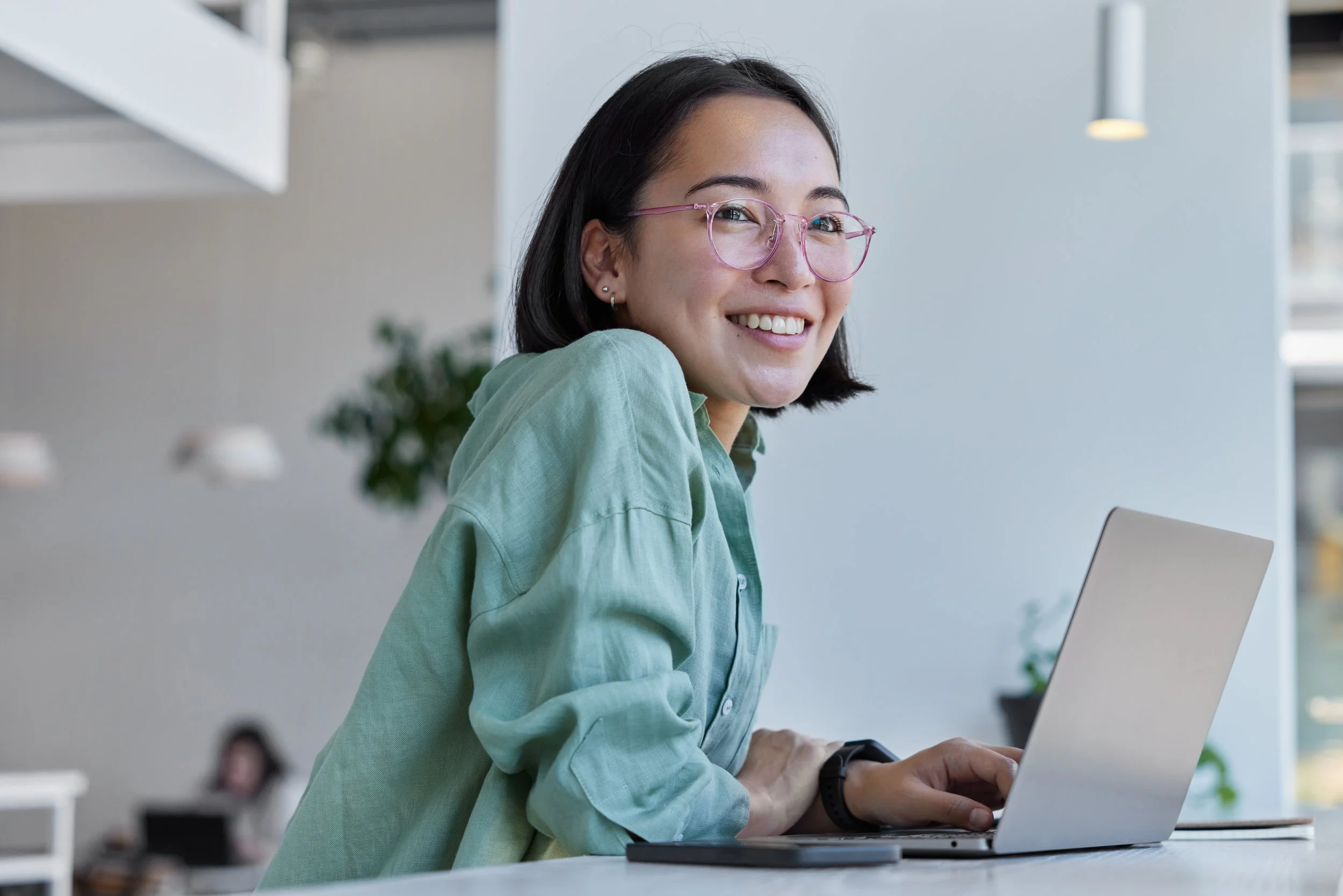woman-with-glasses-smiling-looking-up-from-laptop