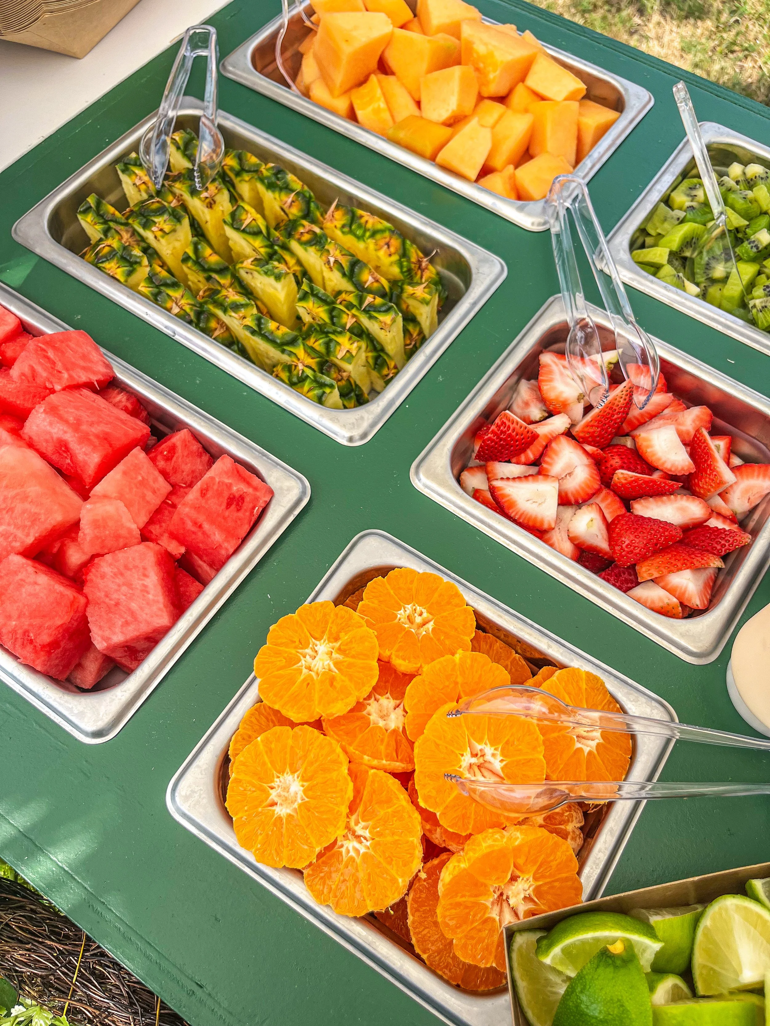 Fruits in a buffet: Watermelon cubes, pineapple pieces, cantaloupe chunks, strawberries, kiwis, and mandarin orange slices.